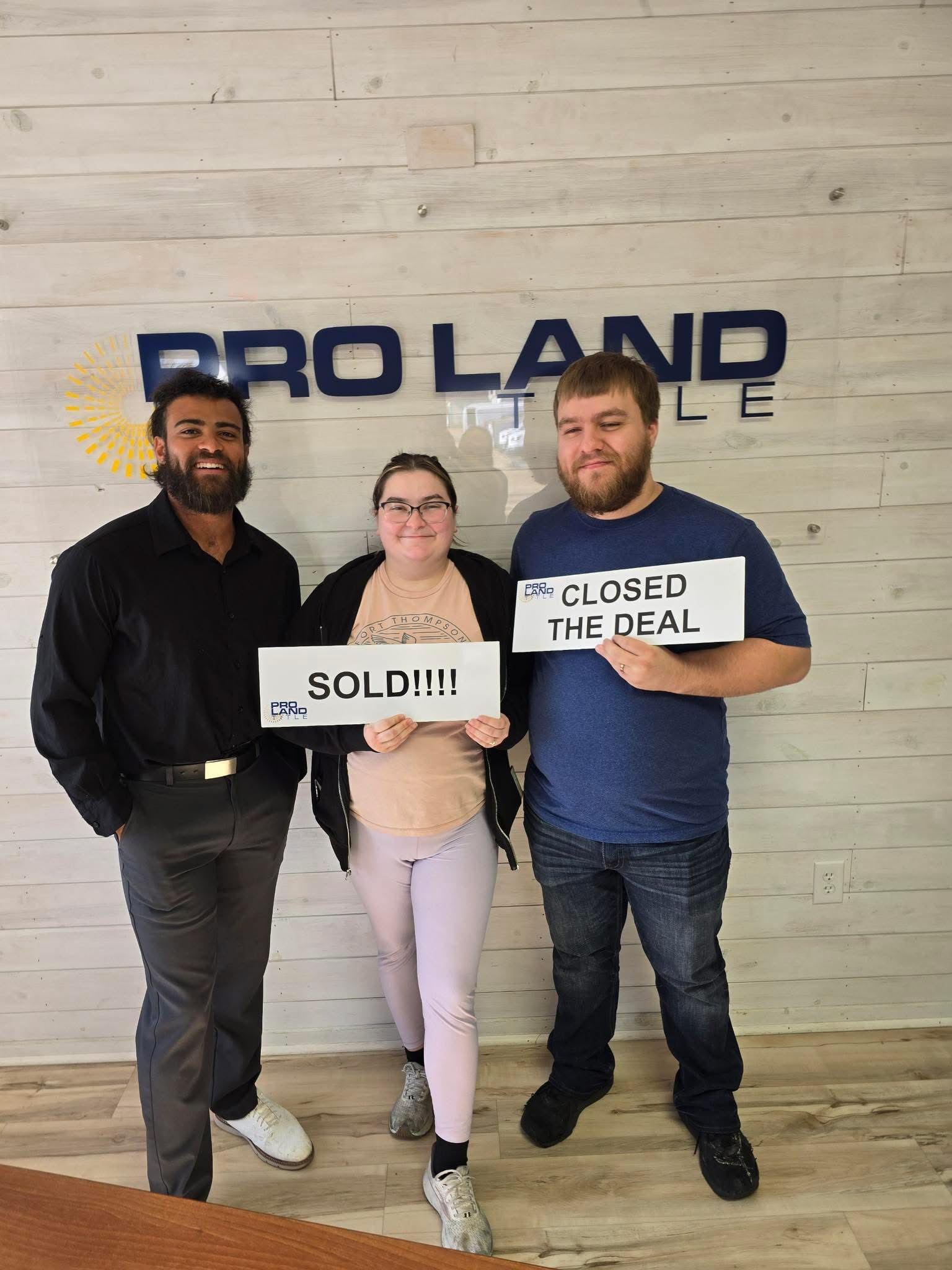 Madison Burke with clients holding sold signs at Pro Land Title